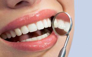 A woman examines her teeth before and after braces using a magnifying glass.