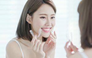 A woman is having fun with braces as she smiles in front of a mirror.