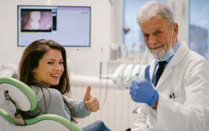 A woman reassuring an older man undergoing a dental examination on oral cancer.